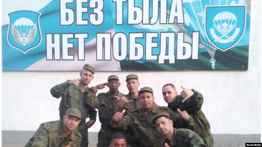 Cubanos en el Regimiento 137 de los paracaidistas rusos. El cartel, escrito en idioma ruso y que indica "Sin retarguardia no hay victoria", incluye el emblema del 137 Regimiento de Paracaidistas (der.) y a la izq. de la 106 División Aerotransportada de las Tropas de Paracaidistas. (Cortesía Alain Paparazzi cubano).