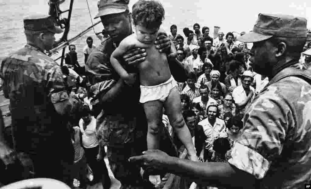 Un marine de EEUU ayuda a desembarcar a un niño cubano tras su llegada a las costas de Florida en el éxodo del Mariel. AP Photo/Fernando Yovera)